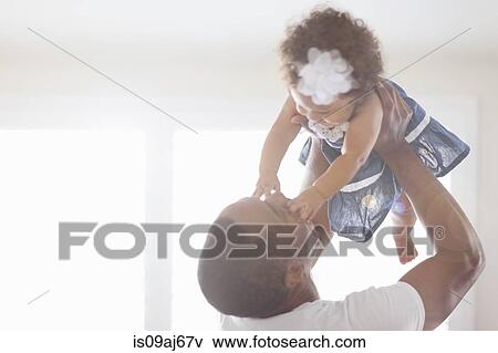 Stock Photo - Father holding baby daughter in the air. Fotosearch