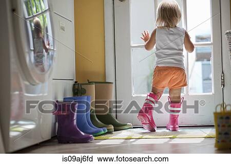Female toddler wearing rubber boots looking out of back door window View Large Photo Image Stock Image - Female toddler wearing rubber boots looking out of back door window. Fotosearch