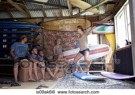 Stock Photograph - Five young adult surfer friends fooling around in surf shed. Fotosearch