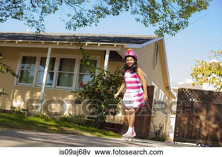 Stock Photo - Girl balancing on skateboard on garden path. Fotosearch