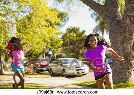 Girl chasing friend with water balloon on street View Large Photo Image Picture - Girl chasing friend with water balloon on street. Fotosearch