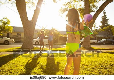 Girl chasing friends with water balloon in garden View Large Photo Image Stock Image - Girl chasing friends with water balloon in garden. Fotosearch
