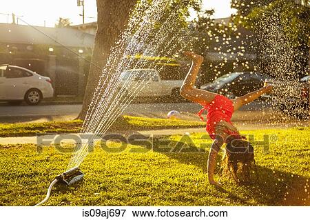 Girl doing handstand under in garden sprinkler View Large Photo Image Stock Photo - Girl doing handstand under in garden sprinkler. Fotosearch