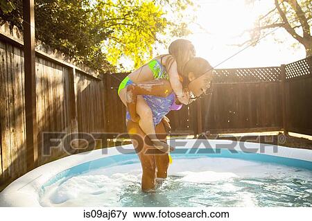 Girl giving friend piggyback in garden paddling pool View Large Photo Image Stock Photo - Girl giving friend piggyback in garden paddling pool. Fotosearch