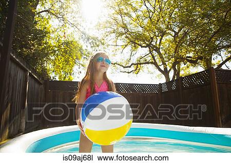 Girl holding beachball in garden paddling pool View Large Photo Image Stock Image - Girl holding beachball in garden paddling pool. Fotosearch