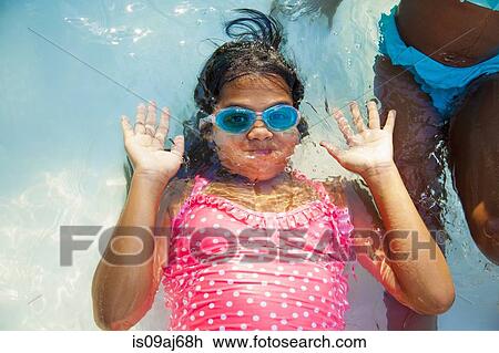 Stock Image - Girl in swimming goggles underwater in garden paddling pool. Fotosearch
