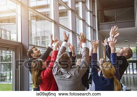 Stock Photography - Group of businesswomen and men raising hands together in a circle. Fotosearch