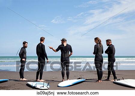 Group of male and female surfer friends chatting on beach View Large Photo Image Stock Image - Group of male and female surfer friends chatting on beach. Fotosearch