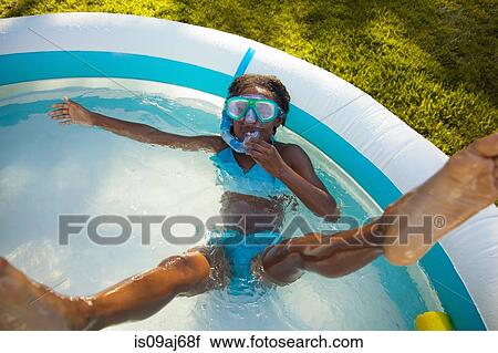 Stock Image - High angle view of girl in snorkel mask in garden paddling pool. Fotosearch