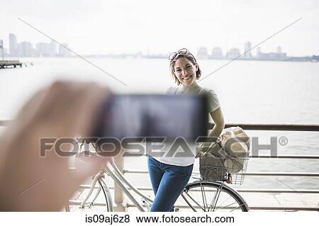 Stock Photo - Male hand photographing girlfriend with smartphone at riverside, New York City, USA. Fotosearch