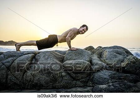 Mid adult man doing push-ups on rocks at beach View Large Photo Image Stock Photograph - Mid adult man doing push-ups on rocks at beach. Fotosearch