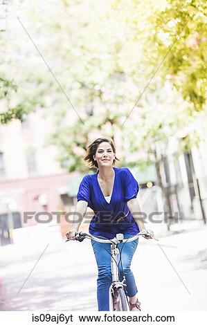 Mid adult woman cycling on city street, New York City, USA View Large Photo Image Stock Photograph - Mid adult woman cycling on city street, New York City, USA. Fotosearch