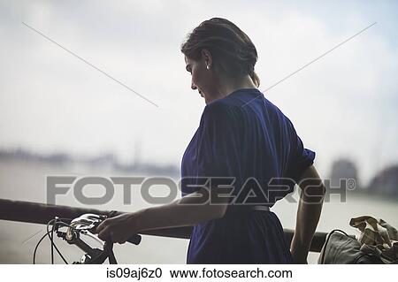 Mid adult woman cyclist pushing bicycle on riverside, New York City, USA View Large Photo Image Stock Image - Mid adult woman cyclist pushing bicycle on riverside, New York City, USA. Fotosearch