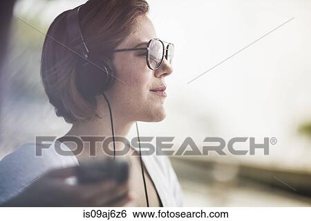 Mid adult woman listening to music on headphones View Large Photo Image Stock Photograph - Mid adult woman listening to music on headphones. Fotosearch
