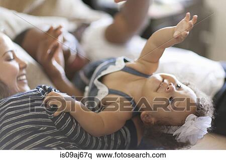 Mother and father lying on bed with baby daughter View Large Photo Image Stock Photography - Mother and father lying on bed with baby daughter. Fotosearch