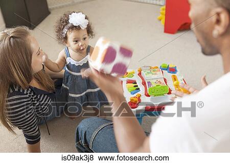 Stock Photo - Mother and father playing with young daughter. Fotosearch
