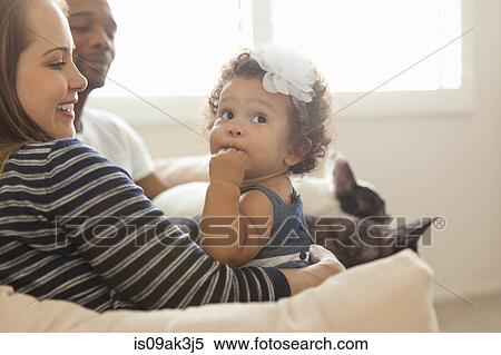 Stock Photography - Mother and father sitting with young daughter. Fotosearch