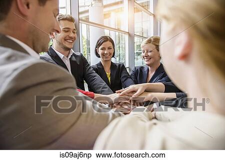 Over shoulder view of group of businesswomen and men smiling with hands together in a circle View Large Photo Image Stock Photography - Over shoulder view of group of businesswomen and men smiling with hands together in a circle. Fotosearch