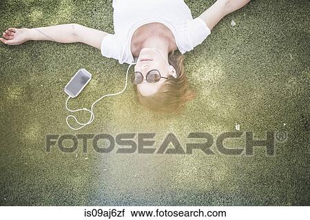 Overhead view of mid adult woman listening to earphones in park View Large Photo Image Stock Image - Overhead view of mid adult woman listening to earphones in park. Fotosearch