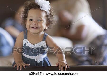 Stock Image - Portrait of baby girl, parents behind. Fotosearch
