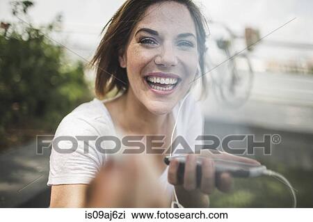 Portrait of laughing mid adult woman holding up earphone View Large Photo Image Stock Image - Portrait of laughing mid adult woman holding up earphone. Fotosearch