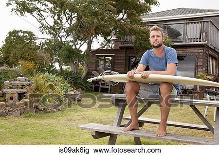 Portrait of male surfer sitting on picnic bench with surfboard on lap View Large Photo Image Stock Image - Portrait of male surfer sitting on picnic bench with surfboard on lap. Fotosearch