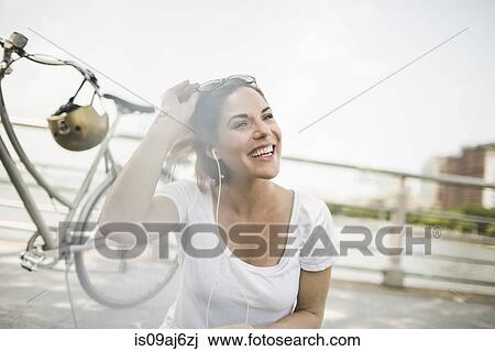 Portrait of smiling mid adult woman cyclist listening to earphones View Large Photo Image Stock Image - Portrait of smiling mid adult woman cyclist listening to earphones. Fotosearch