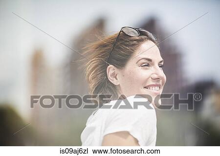 Stock Image - Portrait of smiling mid adult woman with sunglasses in hair. Fotosearch