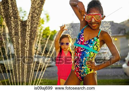 Stock Photo - Portrait of two girls posing with arms raised in garden. Fotosearch