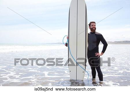 Portrait of young male surfer standing in sea with surfboard View Large Photo Image Stock Image - Portrait of young male surfer standing in sea with surfboard. Fotosearch