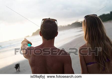 Stock Image - Rear view of couple pointing and looking on beach, Nosara, Guanacaste, Costa Rica. Fotosearch