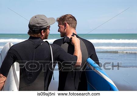 Rear view of male surfer checking his friends wet suit zipper View Large Photo Image Stock Image - Rear view of male surfer checking his friends wet suit zipper. Fotosearch