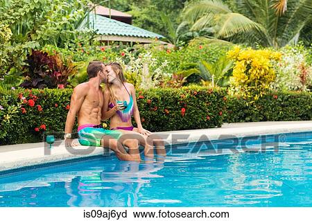 Stock Image - Romantic couple kissing by swimming pool, Nosara, Guanacaste, Costa Rica. Fotosearch