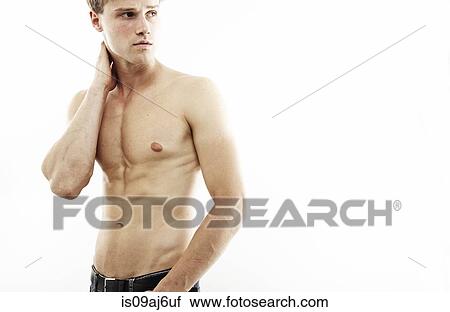 Stock Image - Studio portrait of muscular bare chested young man looking over his shoulder. Fotosearch