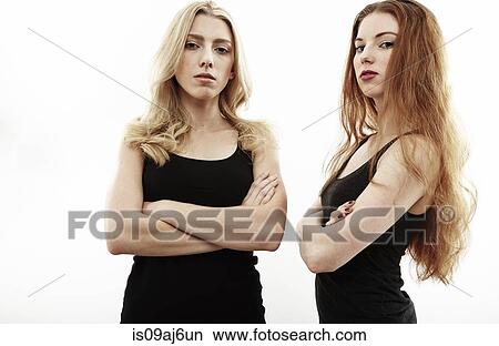 Picture - Studio portrait of two young woman with arms folded. Fotosearch