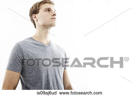 Stock Image - Studio portrait of young man gazing upward. Fotosearch