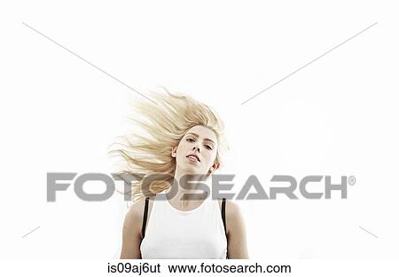 Stock Photograph - Studio portrait of young woman shaking long blond hair. Fotosearch