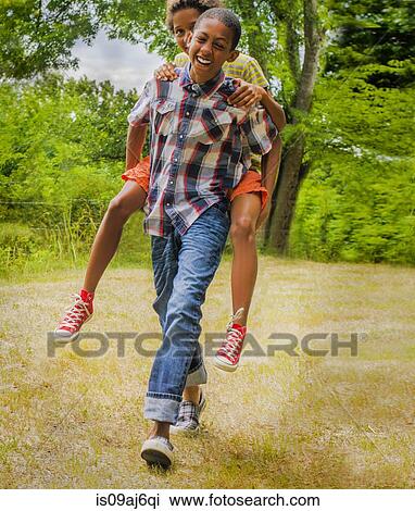 Teenage boy giving friend piggyback ride View Large Photo Image Stock Image - Teenage boy giving friend piggyback ride. Fotosearch