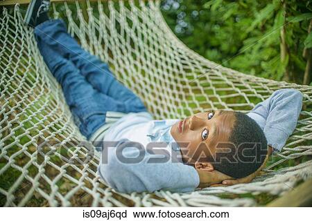 Stock Image - Teenage boy lying in hammock. Fotosearch