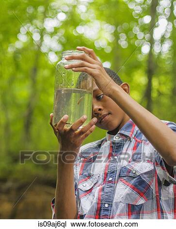 Stock Image - Teenage boy with fish in jar. Fotosearch