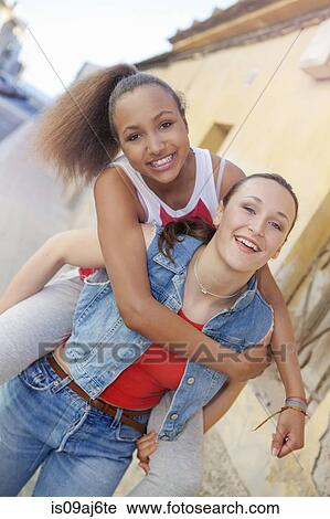 Teenage girl giving friend piggyback ride View Large Photo Image Stock Image - Teenage girl giving friend piggyback ride. Fotosearch