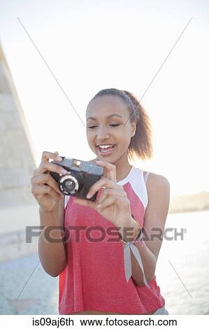 Stock Image - Teenage girl preparing camera. Fotosearch