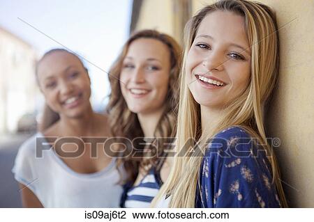 Stock Image - Teenage girls in street by side of house. Fotosearch