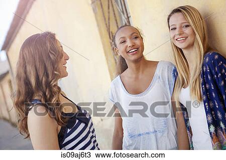 Stock Image - Teenage girls in street by side of house. Fotosearch