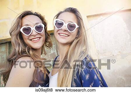Stock Photo - Teenage girls wearing heart-shaped sunglasses. Fotosearch