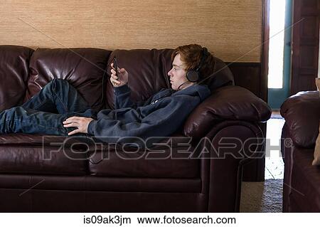 Picture - Teenager listening to mp3 music player at home. Fotosearch