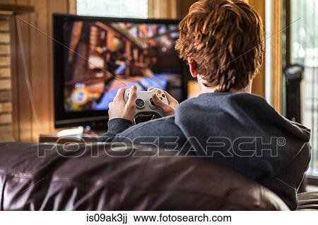 Stock Image - Teenager playing video games at home. Fotosearch