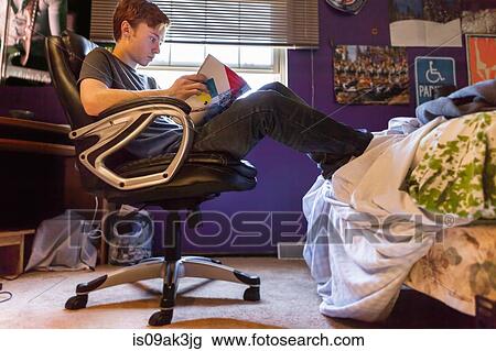 Stock Image - Teenager reading magazine at home. Fotosearch