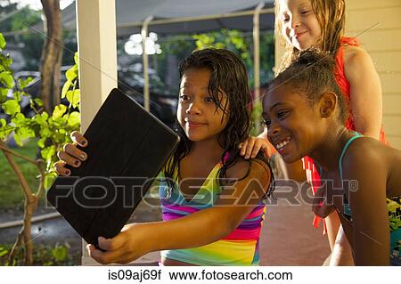 Three girls in porch looking at digital tablet View Large Photo Image Stock Image - Three girls in porch looking at digital tablet. Fotosearch