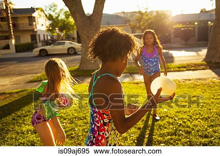 Three girls playing with water balloons in garden View Large Photo Image Stock Photography - Three girls playing with water balloons in garden. Fotosearch